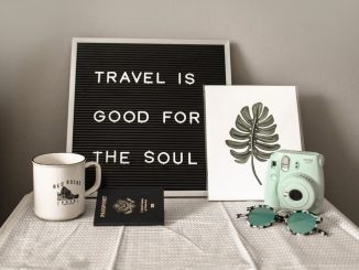 A travel-themed flat lay with a camera, coffee, and motivational quote.